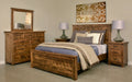 Handstone Adirondack bedroom set in wormy maple with a Sawmill Harvest finish, featuring a wood bed, matching dresser with framed mirror, and three-drawer nightstands. Warm cognac tones, distinctive natural wood grain, and dark metal hardware complete the rustic design.