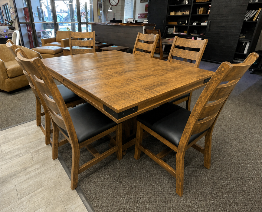 rustic solid maple dining table with a warm barley coloured finish and black metal corner bracket accents, with 6 matching ladderback chairs that have black upholstered seats