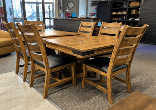 rustic solid maple dining table with a warm barley coloured finish and black metal corner bracket accents, with 6 matching ladderback chairs that have black upholstered seats