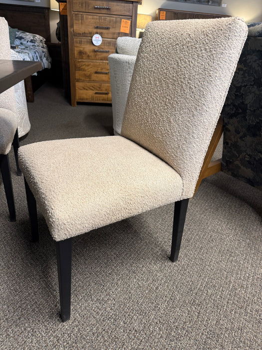 Kenova upholstered dining chair in boucle textured ivory fabric with a gently angled high back, cushioned seat, and slender tapered black metal legs.