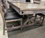 rustic dining table featuring a trestle-style base, and matching wooden chairs with dark upholstered seats